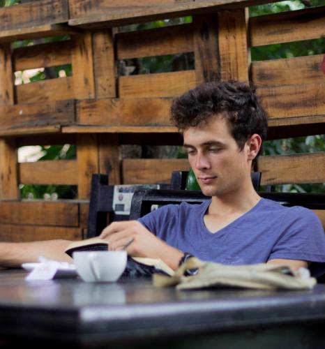 a young man sitting at a table reading a book at Wander Thirst in Kathmandu