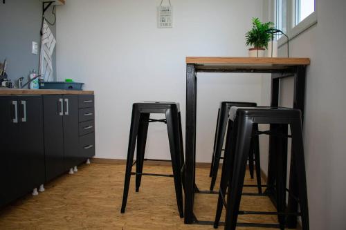 two black bar stools under a table with a plant on it at OPG Dokić in Kopačevo