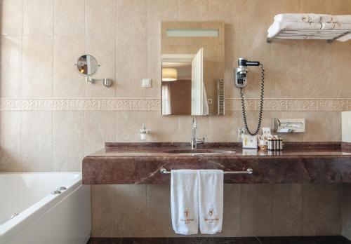 a bathroom with a sink and a tub and a mirror at Palace Del Mar in Odesa