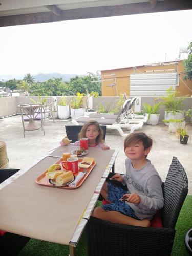 two children sitting at a table with a tray of food at Residence Les Bambous in Mahébourg
