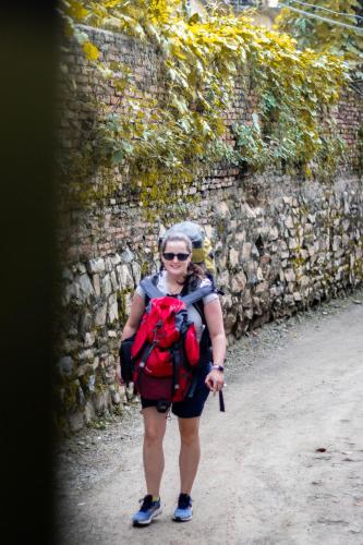 a woman walking down a dirt road with a backpack at Wander Thirst in Kathmandu