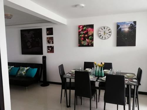 a dining room with a table and chairs and a clock at Guaduales del café 511 A en montenegro in Montenegro