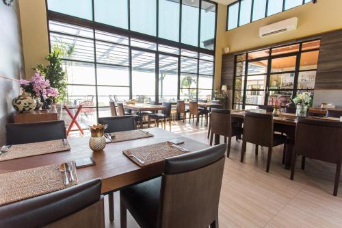 a restaurant with wooden tables and chairs and windows at Pawanthorn Samui - SHA Plus in Chaweng