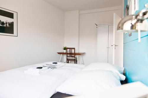 a white bedroom with a bed and a chair at Green Residence Boutique Lofts & Villa am Park in Offenbach