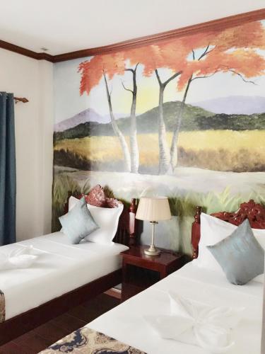 a bedroom with two beds with a painting on the wall at Blue Waters Inn Coron Palawan in Coron