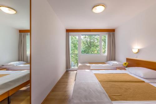 a row of beds in a room with a window at Holiday Resort Kačjak in Dramalj