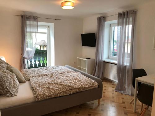a bedroom with a bed and two windows at SPITZAUERs APARTMENTs in Anthering
