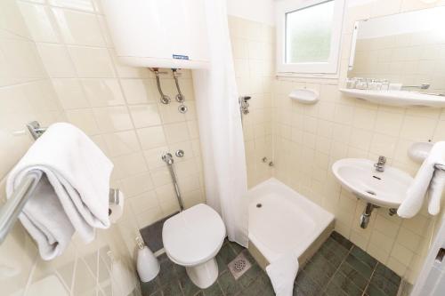 a white bathroom with a toilet and a sink at Holiday Resort Kačjak in Dramalj