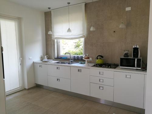 a kitchen with white cabinets and a microwave at La Conchiglia in Petrosino