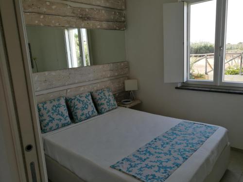 a bedroom with a bed with blue pillows and a window at La Conchiglia in Petrosino