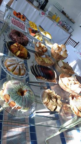 une table remplie de différents types de pâtisseries dans l'établissement Pousada Praia de Bombinhas, à Bombinhas