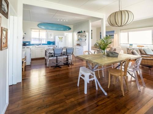 a kitchen and dining room with a wooden table and chairs at Tallowood beachfront cottage in Bonny Hills