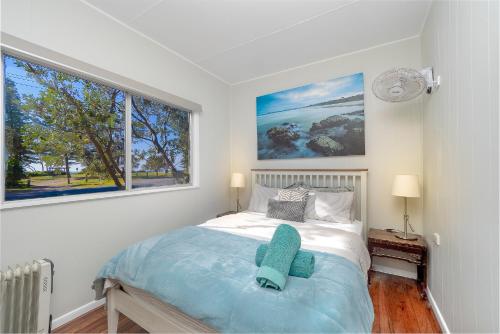 a bedroom with a bed with a blue pillow on it at Tallowood beachfront cottage in Bonny Hills