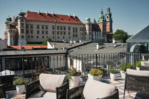 a balcony with chairs and potted plants and buildings at Hotel Copernicus in Krakow