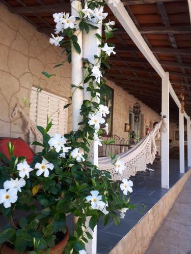 a porch with a swing and white flowers at Pousada Vale da Serra in Serra Negra