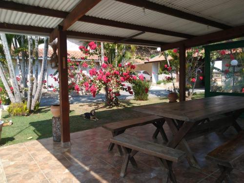 a wooden picnic table under a pavilion with pink flowers at Pousada Vale da Serra in Serra Negra