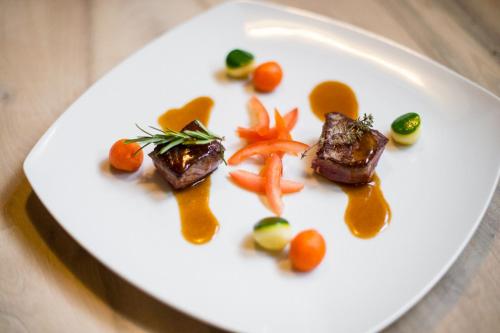a white plate with meat and vegetables on it at Natur Pur Hotel Unterpichl in Ultimo
