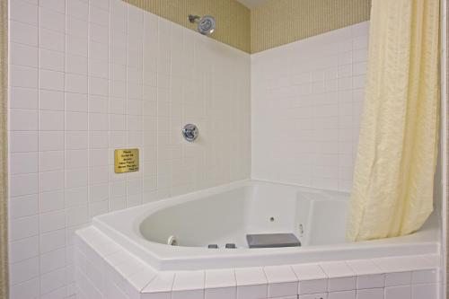 Quality Inn I-75 West Chester-North Cincinnati في ويست تشيستر: حوض استحمام أبيض في حمام من البلاط الأبيض