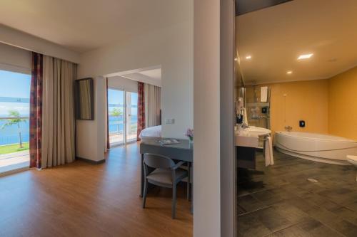 a hotel room with a bathroom with a tub and a bedroom at Engenho Velho Hotel. Restaurante in Arco da Calheta