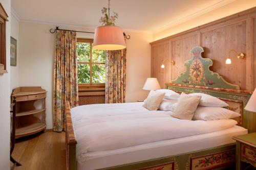 - une chambre avec un grand lit blanc et une fenêtre dans l'établissement Landsitz Römerhof - Hotel Apartments, à Kitzbühel