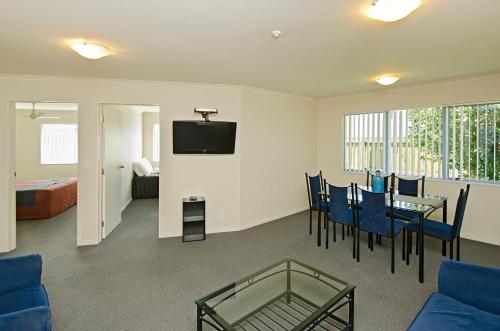 a living room with a table and chairs and a television at Gateway Motor Inn in Mount Maunganui