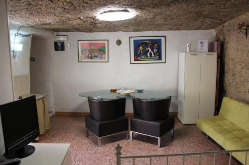 a room with a table and chairs and a television at Camera Nella Roccia in Tropea