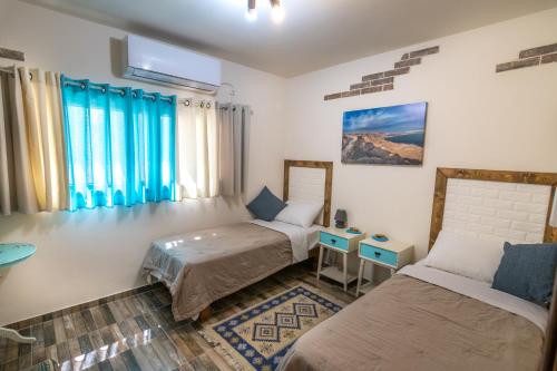 een kamer met 2 bedden, een tafel en ramen bij Desert Picture in Arad