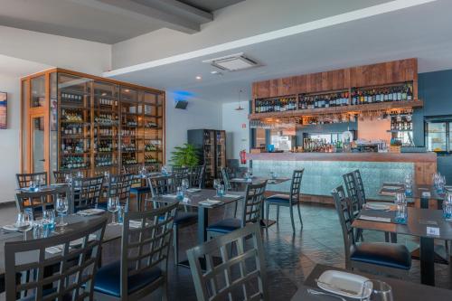 a restaurant with tables and chairs and a bar at Engenho Velho Hotel & Restaurante - Adults Only in Arco da Calheta