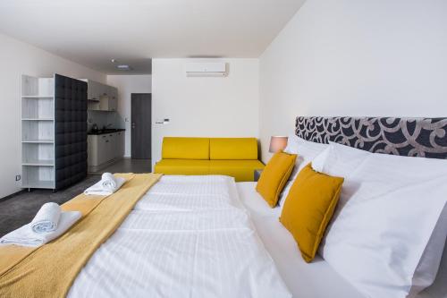 sypialnia z dużym białym łóżkiem z żółtymi poduszkami w obiekcie Penzion Čáp w mieście Mikulov