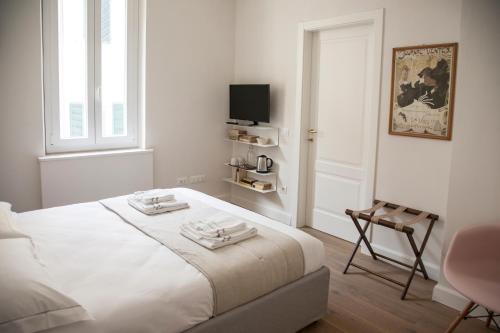 a white bedroom with a bed and a chair at Pietrapiana34 Boutique Apartments in Florence