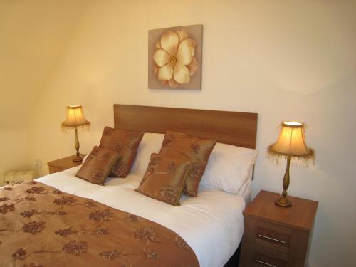 1 dormitorio con 1 cama con almohadas y 2 lámparas en Measure Cottage - Sleeps 5 - Private Hot tub and garden en Henley in Arden