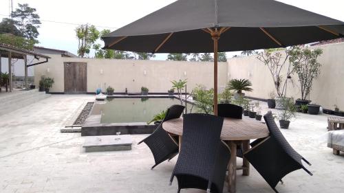 a table and chairs with an umbrella next to a pool at Omah SunFlower in Yogyakarta