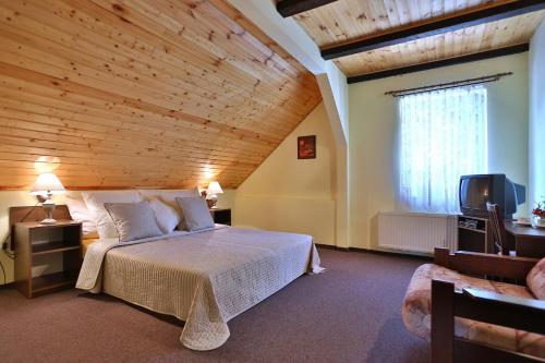 ein Schlafzimmer mit einem großen Bett und einer Holzdecke in der Unterkunft Tradice (U Bendů) in Pernink