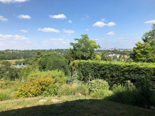 a garden with hedges and a view of a city at Les Agapanthes Site de Fondettes in Fondettes