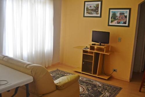 sala de estar con sofá y TV en Hotel Ampiezza, en Curitiba