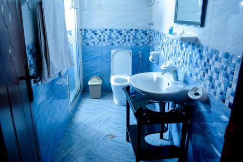 W wyłożonej niebieskimi kafelkami łazience znajduje się umywalka i toaleta. w obiekcie Melodie Hotel w Addis Abebie