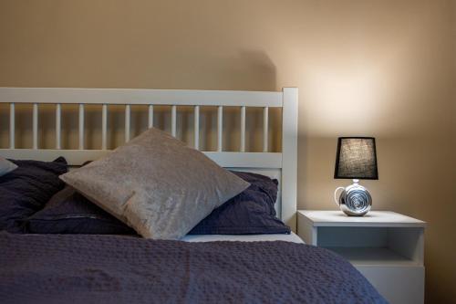 a bed with a pillow and a lamp on a night stand at Virág Vendégház in Makó