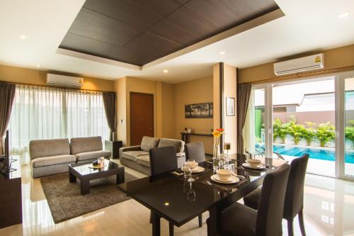 
a living room filled with furniture and a large window at The Ville Jomtien Pool Villa in Jomtien Beach
