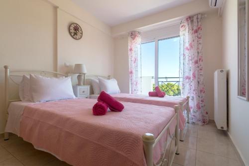 1 Schlafzimmer mit 2 Betten mit rosa Bettwäsche und einem Fenster in der Unterkunft Lovely Apartment Xylokastro 4th Floor in Xylokastro