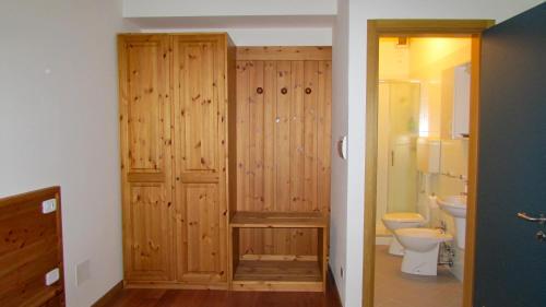 a bathroom with a toilet and a wooden wall at La casa del popolo in Prato Carnico