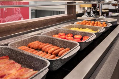 a buffet line with trays of tomatoes and other foods at Ramada by Wyndham Cobham in Cobham
