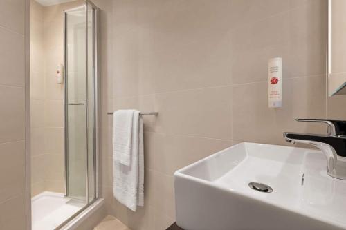 a bathroom with a shower, sink, and toilet at Ramada by Wyndham Cobham in Cobham