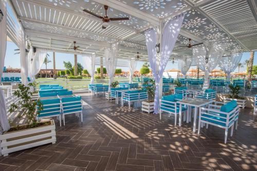 Sunrise Royal Makadi Resort في الغردقة: مروش بكراسي زرقاء وطاولات ومظلات بيضاء