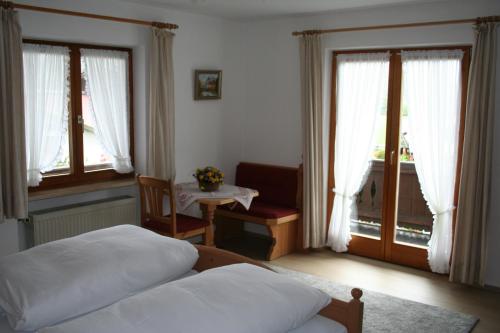 a bedroom with two beds and a table and windows at Gästehaus Sonnenbichl in Reit im Winkl
