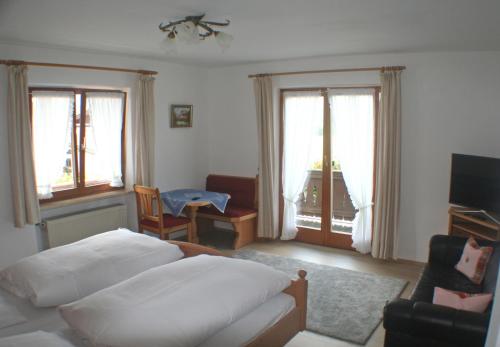 a bedroom with a bed and a chair and windows at Gästehaus Sonnenbichl in Reit im Winkl