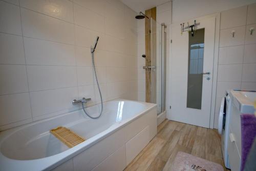 La salle de bains est pourvue d'une baignoire blanche et d'une douche. dans l'établissement Salotto di LaZia, à Bad Schallerbach