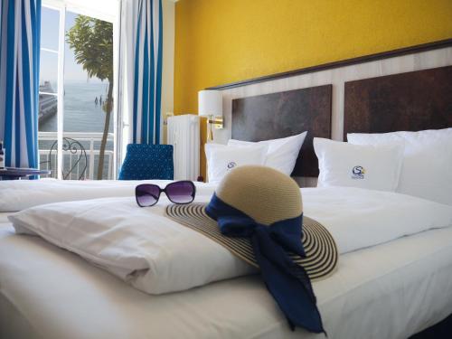 a hotel room with a bed with a hat and sunglasses at Hotel & Gästehaus Seehof in Meersburg