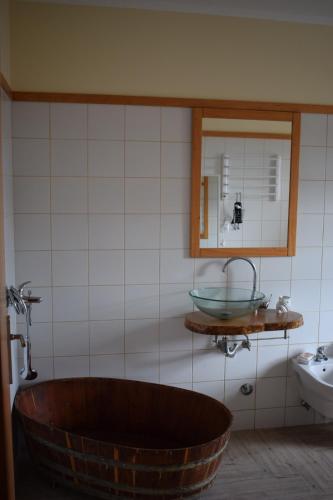 a bathroom with a large wooden tub next to a sink at Casinha da Avó Jerónima RRAL 1519 in Madalena