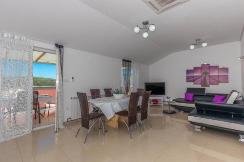 uma sala de estar com uma mesa e um sofá em Villa Rossa Apartments em Rab
