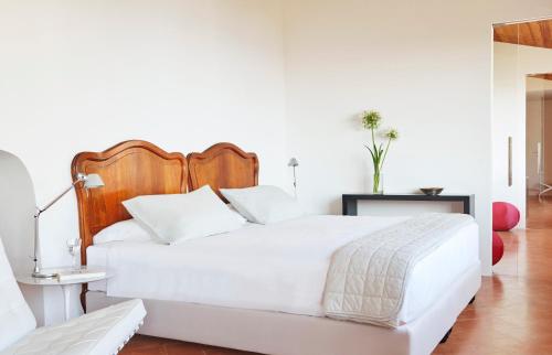 a bedroom with a white bed with a wooden headboard at Villa Paola in Tropea